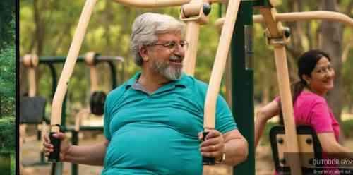 An elderly couple using park exercise equipment at Signature Global Titanium Sector 71 Gurgaon outdoor gym.